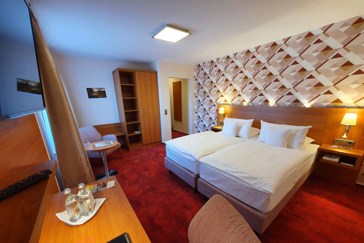 Habitación de hotel con una cama grande, un escritorio con silla, un armario y un televisor.