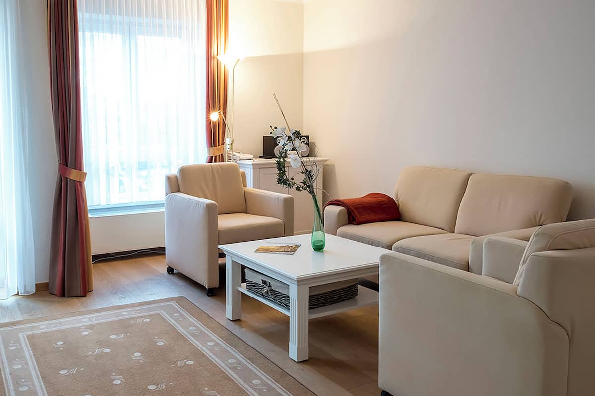 A living room with a sofa, armchairs, a coffee table, and a rug.