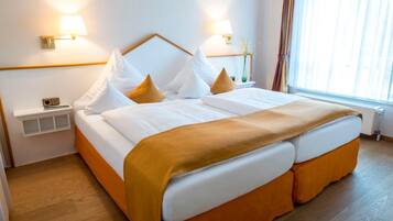 A hotel room with a large bed, two bedside lamps, a nightstand, and a window with curtains.