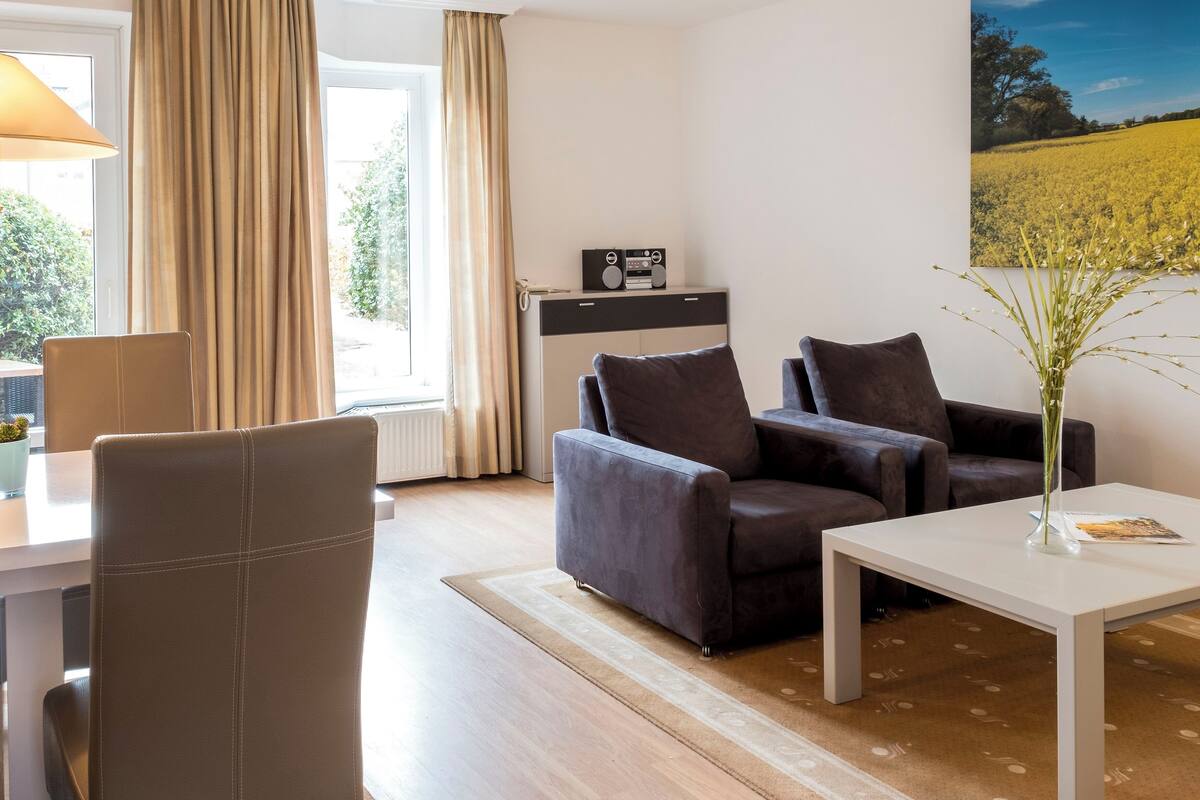 A modern living room with a sofa, a coffee table, and a dining area with a table and chairs.