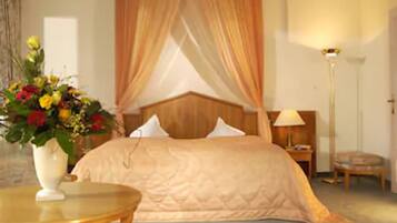 A bedroom with a bed, a bedside table, a lamp, and a vase with flowers.