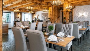 Un restaurante con vigas de madera, candelabros y mesas impecablemente dispuestas.