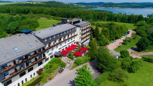 Un hotel con varios pisos, zonas de estar al aire libre y vistas a un lago.