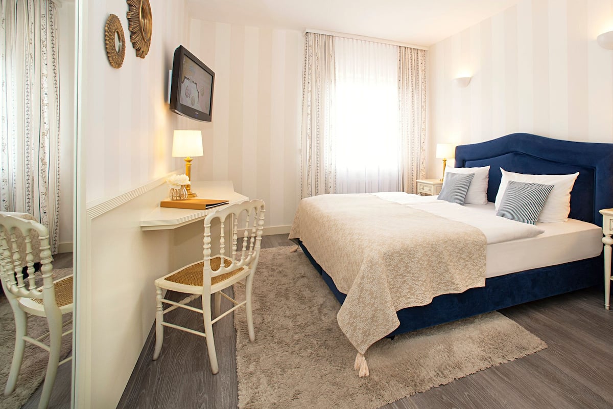 Une chambre à coucher avec un grand lit, deux tables de chevet, une chaise et un bureau.