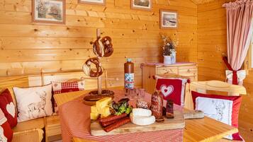 Interior de cabana de madeira com mesa posta, com pretzels, queijo e salsichas.