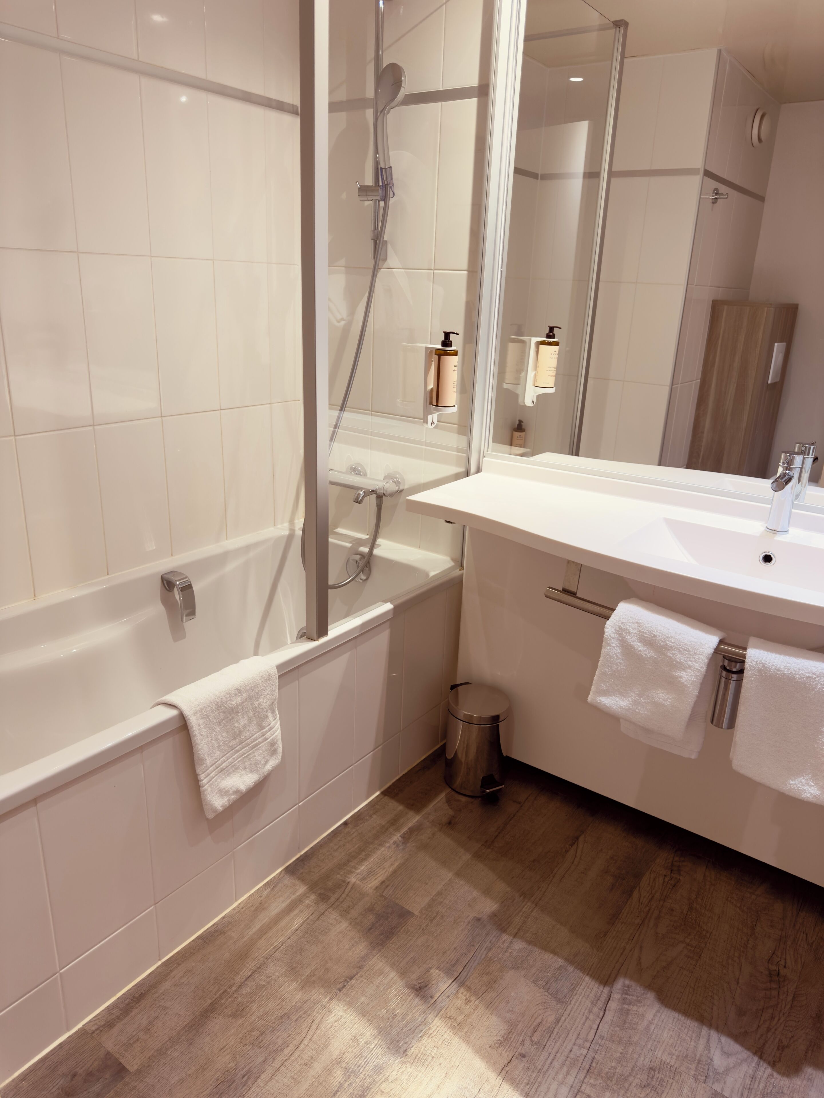 A modern bathroom with a bathtub, shower, and vanity.