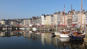 A harbor with boats docked, reflecting the buildings and sky. - Mercure Rouen Val De Reuil (Val-de-Reuil)