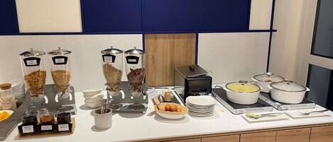 A buffet setup with various food dispensers, plates, and hot dishes.