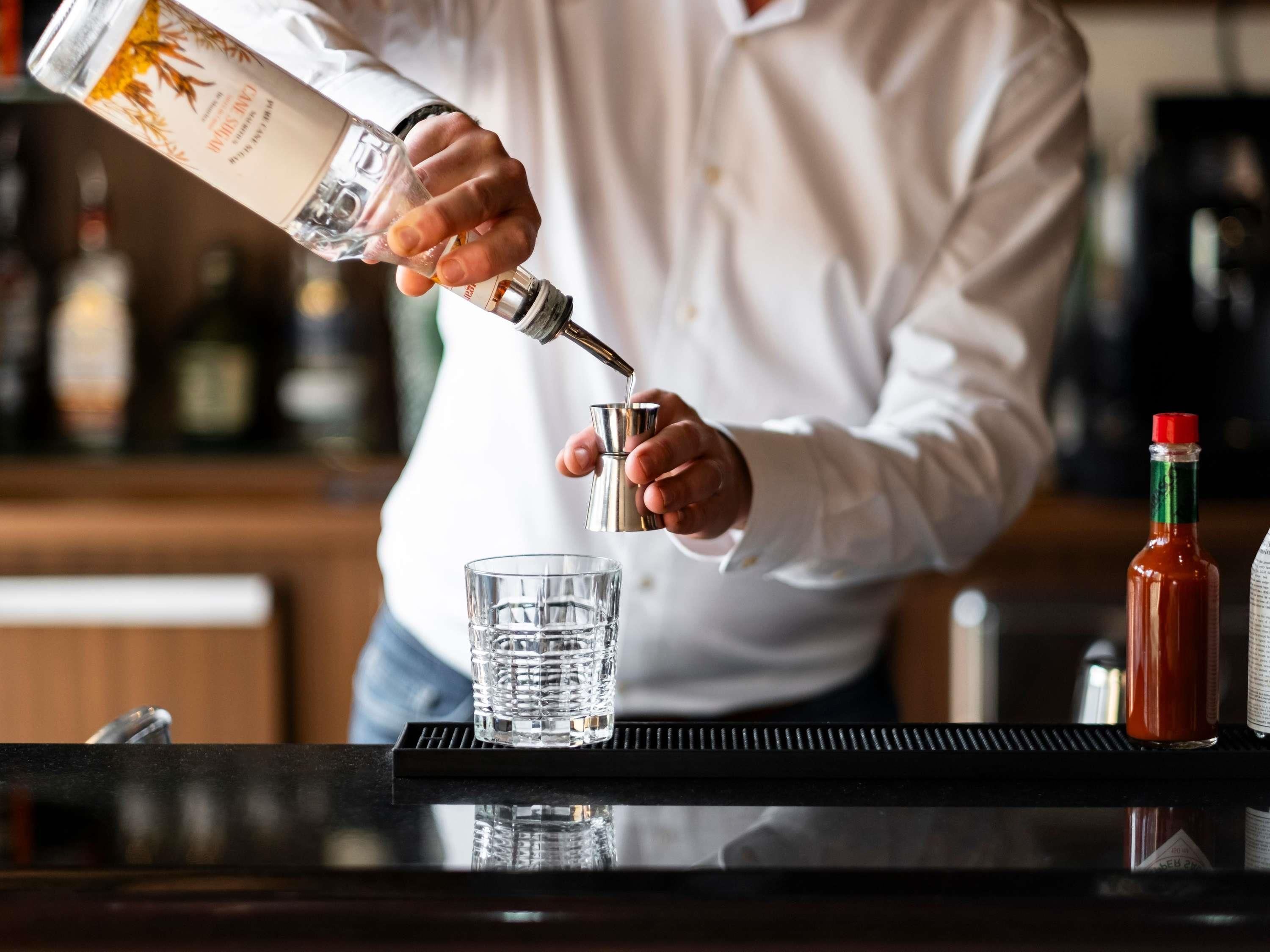 Une personne verse un liquide transparent dans un verre.