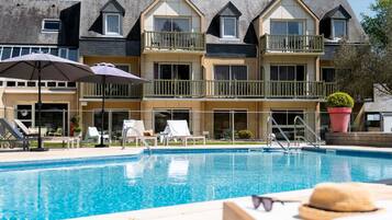 Een buitenzwembad, parasols bij het zwembad en ligstoelen