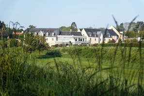 A large, multi-story building with a symmetrical facade, surrounded by well-maintained lawns and trees. - Mercure Omaha Beach Hotel (Port-en-Bessin-Huppain)