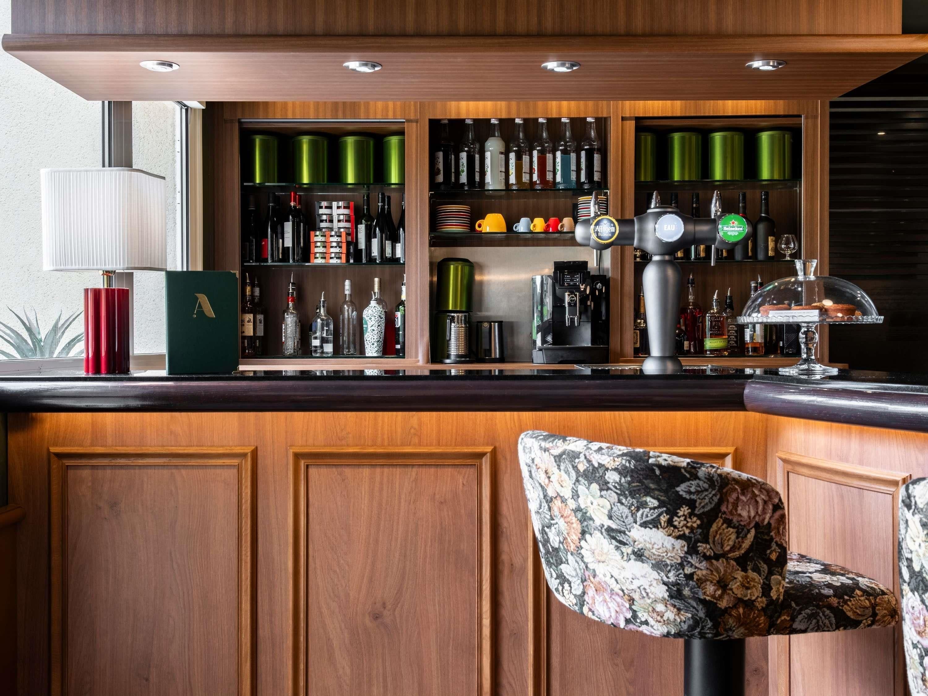 Un espace bar doté de meubles en bois, d’une machine à café et d’une variété de bouteilles et de verres.