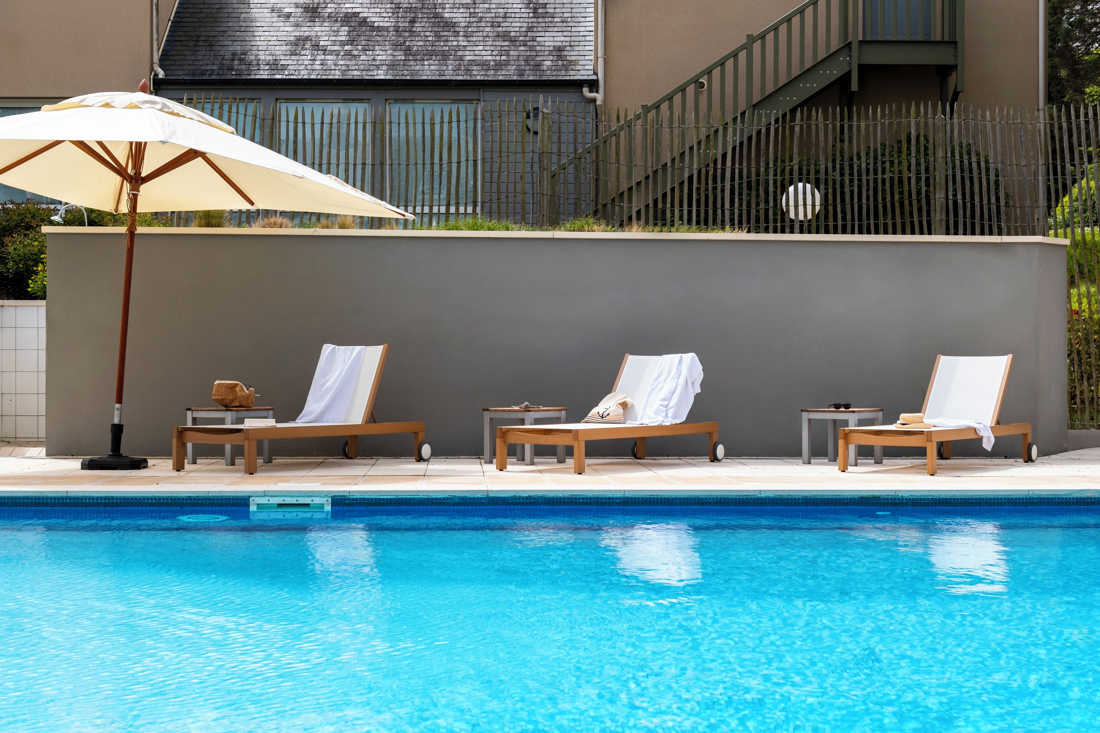 A swimming pool with lounge chairs and an umbrella.