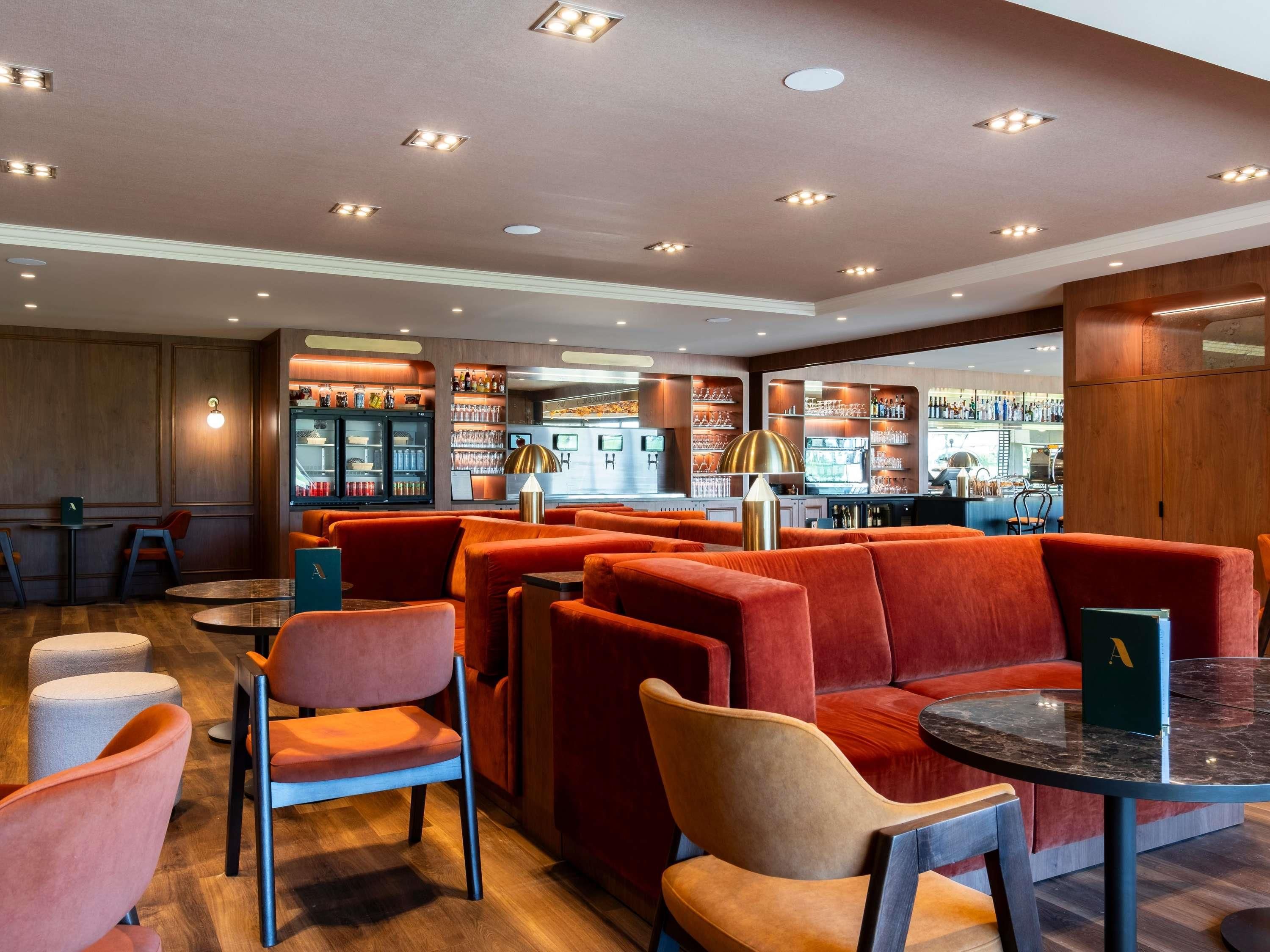 Un espace bar moderne, doté de sièges et d’un comptoir.