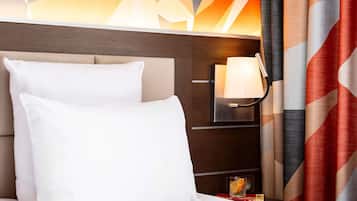 Une chambre d’hôtel avec un lit, une table de chevet, une lampe et un mur orné de motifs géométriques.