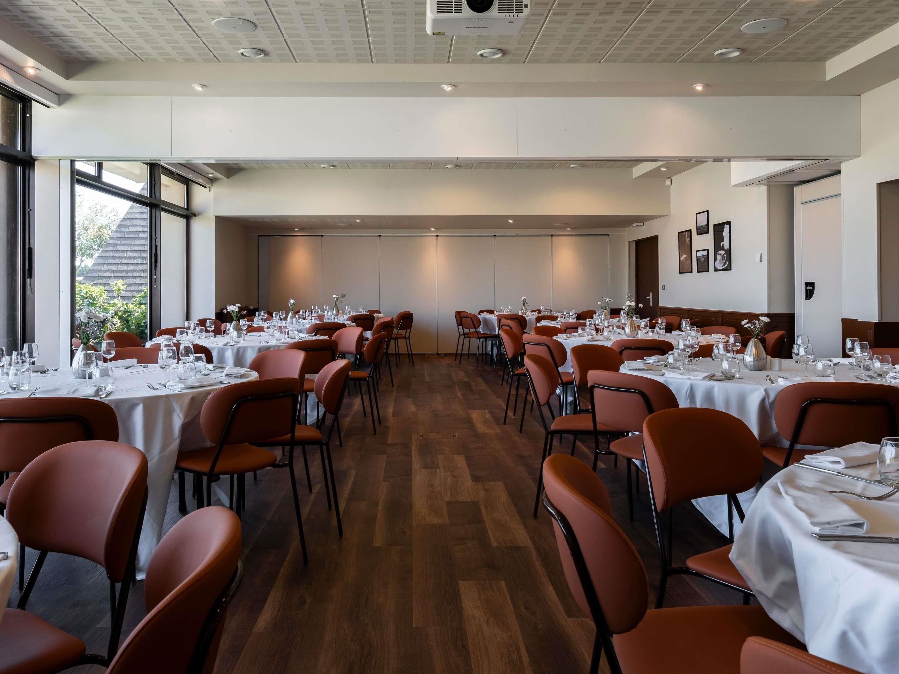 Un salón de conferencias con varias mesas dispuestas para comer, equipado con sillas y mesas.