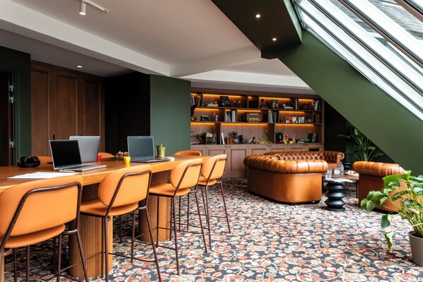 A modern interior with a dining area, a leather sofa, and a bookshelf. - Mercure Omaha Beach Hotel (Port-en-Bessin-Huppain)