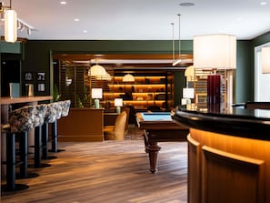 A modern hotel lobby with a pool table, bar area, and seating.