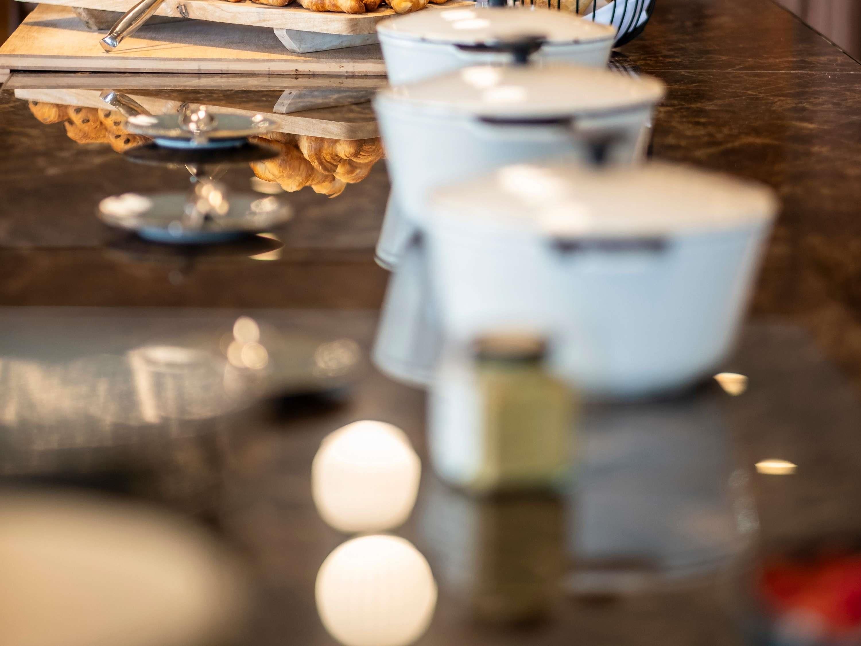 Une table à manger avec un plateau en verre, un pichet blanc et une assiette de nourriture.