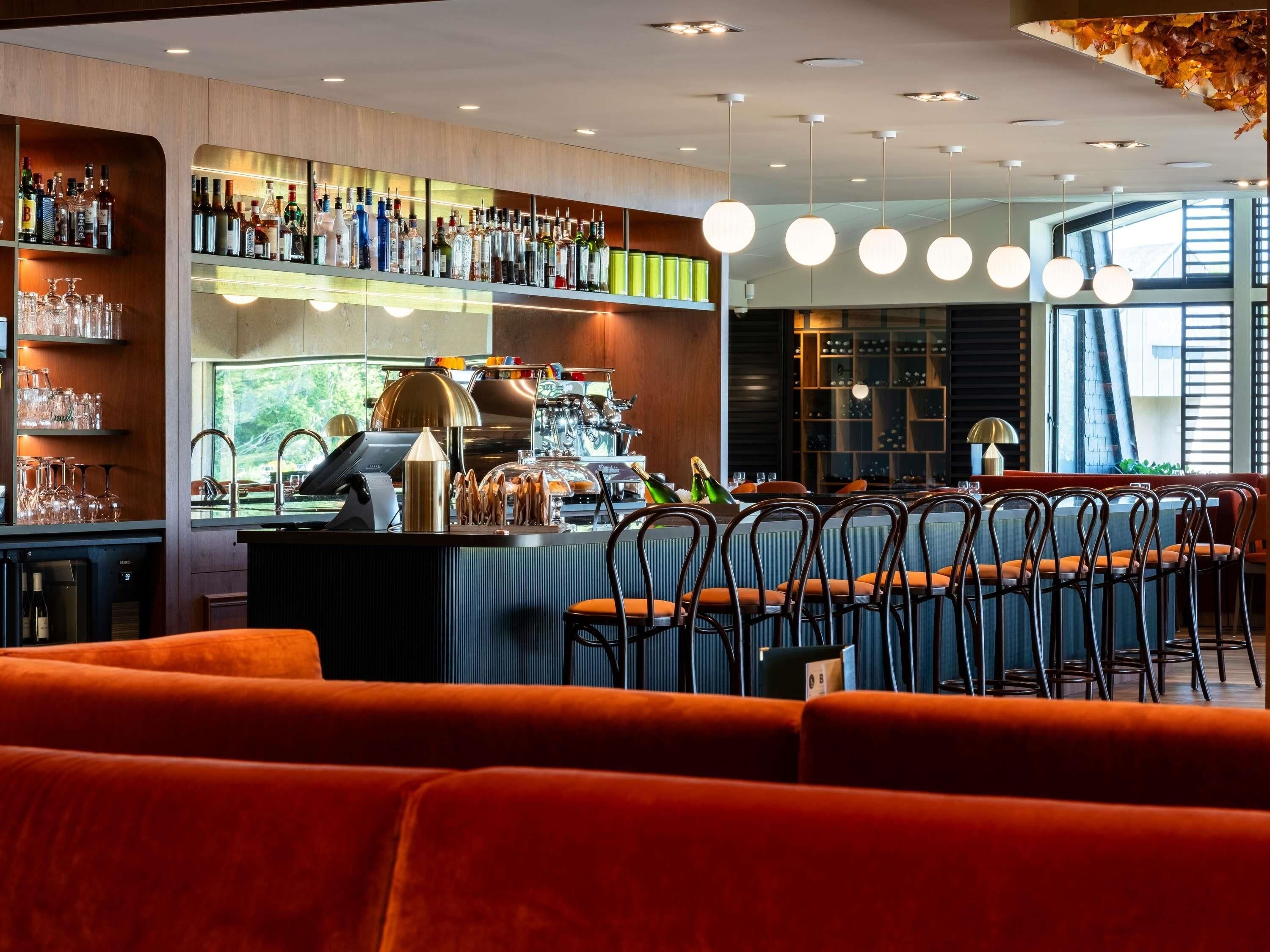 A bar area with a counter, shelves with bottles, and a seating area with chairs.