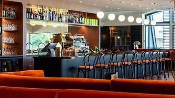 A bar area with a counter, shelves with bottles, and a seating area with chairs.