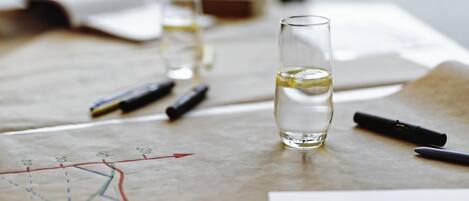 A glass of water on a table with a map and pens.