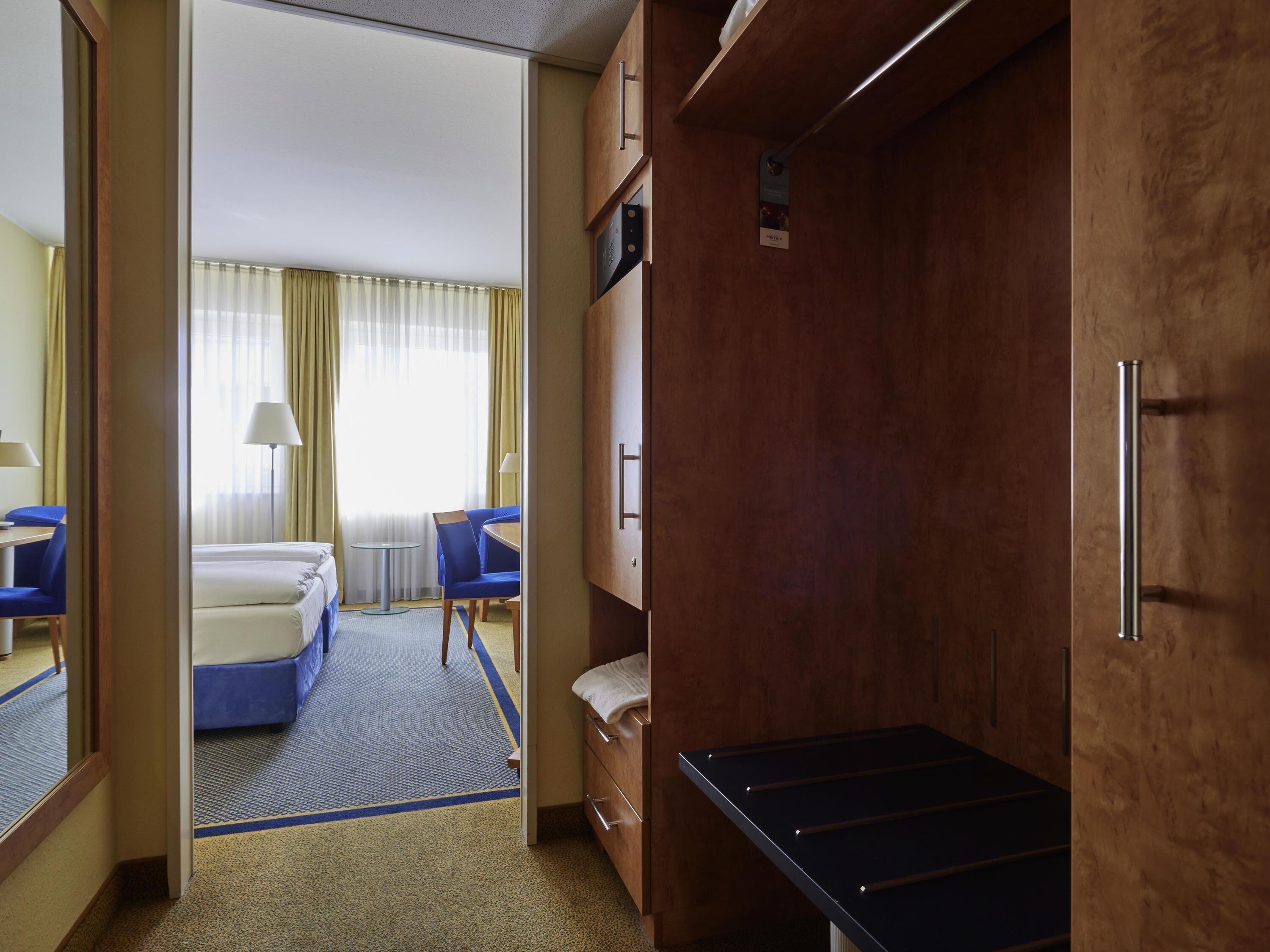 Een hotelkamer met een bed, bureau, stoel, klein tafeltje en een garderobe.