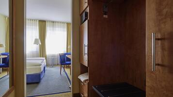 Een hotelkamer met een bed, bureau, stoel, klein tafeltje en een garderobe.