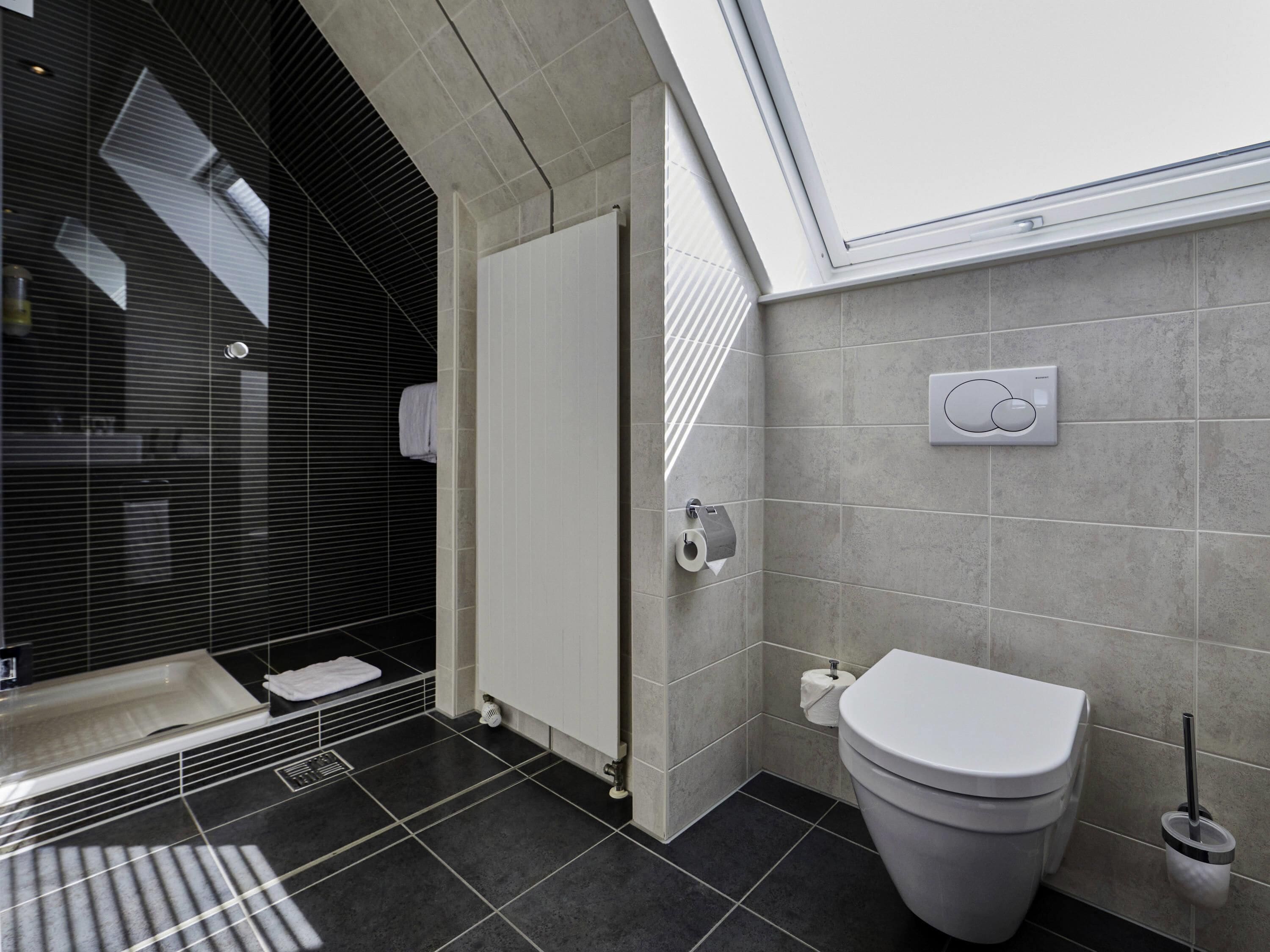 A modern bathroom with a shower, toilet, and a towel rack.