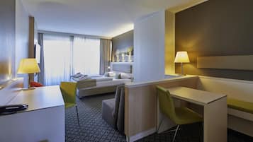 Une chambre d’hôtel comprenant un lit, un bureau, une chaise, un canapé et une table de chevet.
