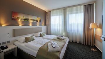 A hotel room with a large bed, a nightstand, a lamp, and a painting on the wall.