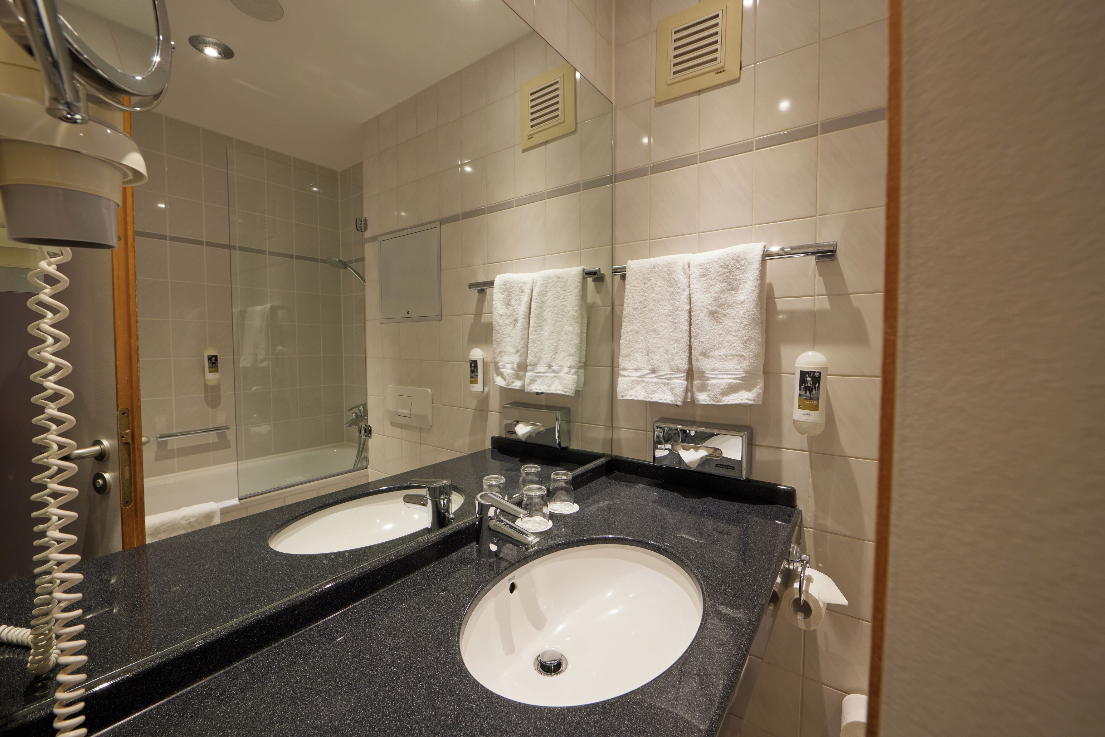 Un baño con dos lavamanos, un espejo y una ducha.