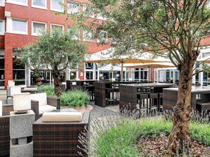 Un espace extérieur aménagé avec des meubles en osier et un arbre.