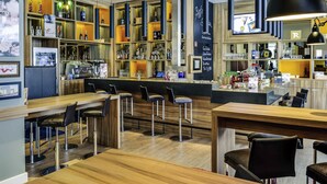 Un espace bar avec des meubles en bois, des étagères remplies de bouteilles et un écran de télévision.