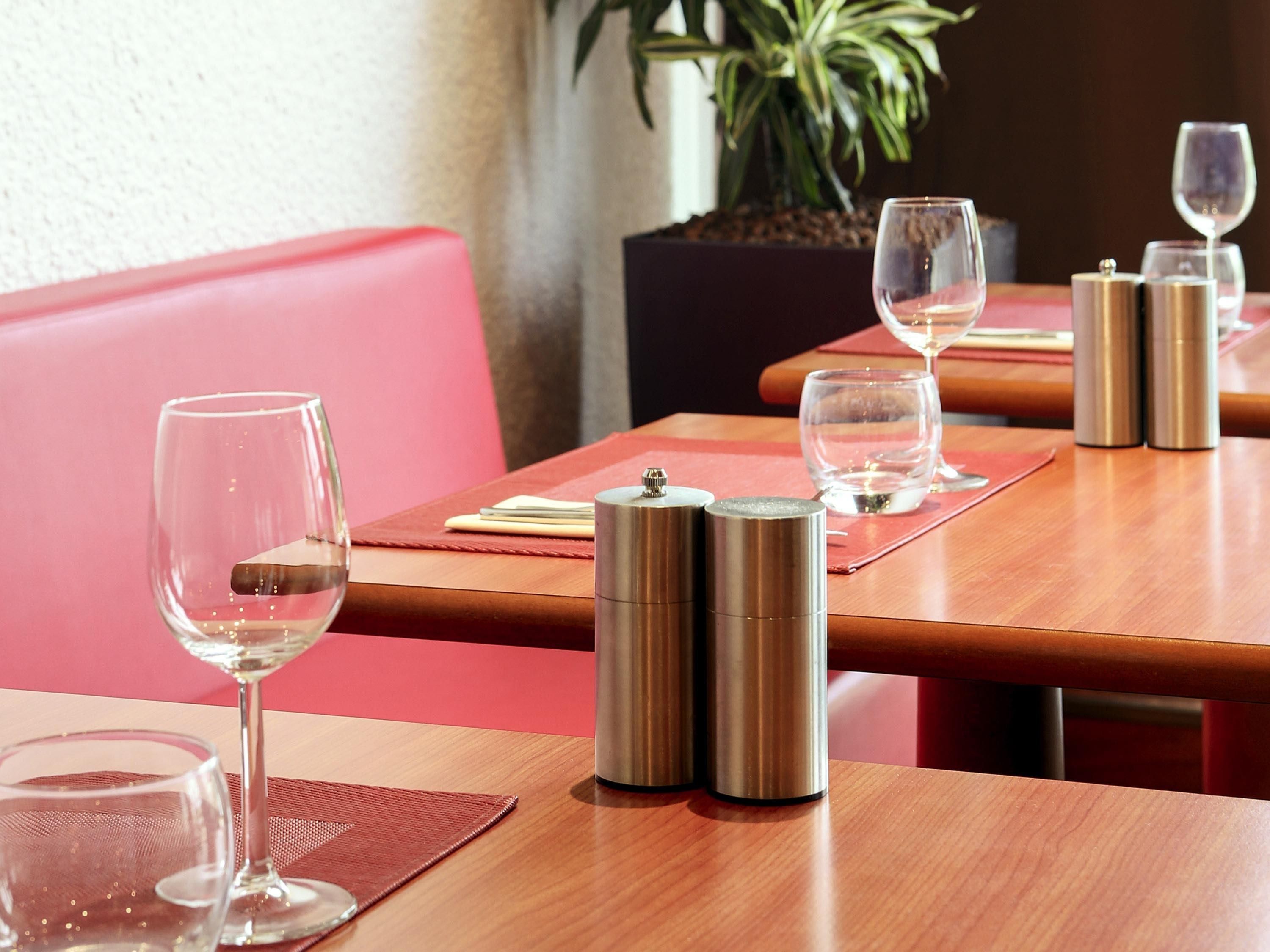 A restaurant setting with tables, wine glasses, and thermos flasks.