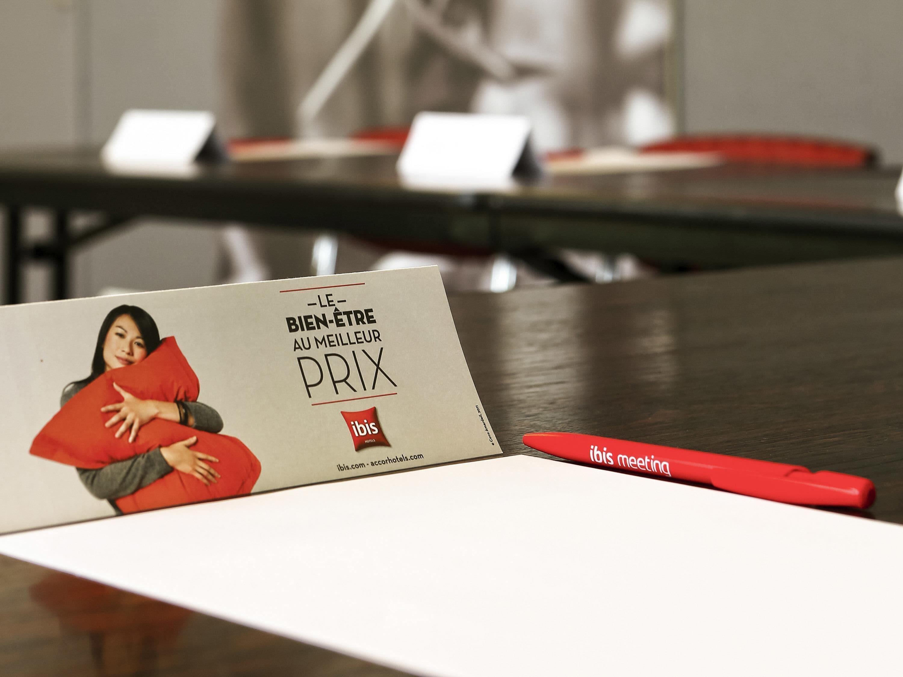 Un biglietto da visita con testo e un logo, appoggiato su un tavolo con una penna rossa accanto.