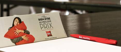 A business card with text and a logo, placed on a table with a red pen beside it.