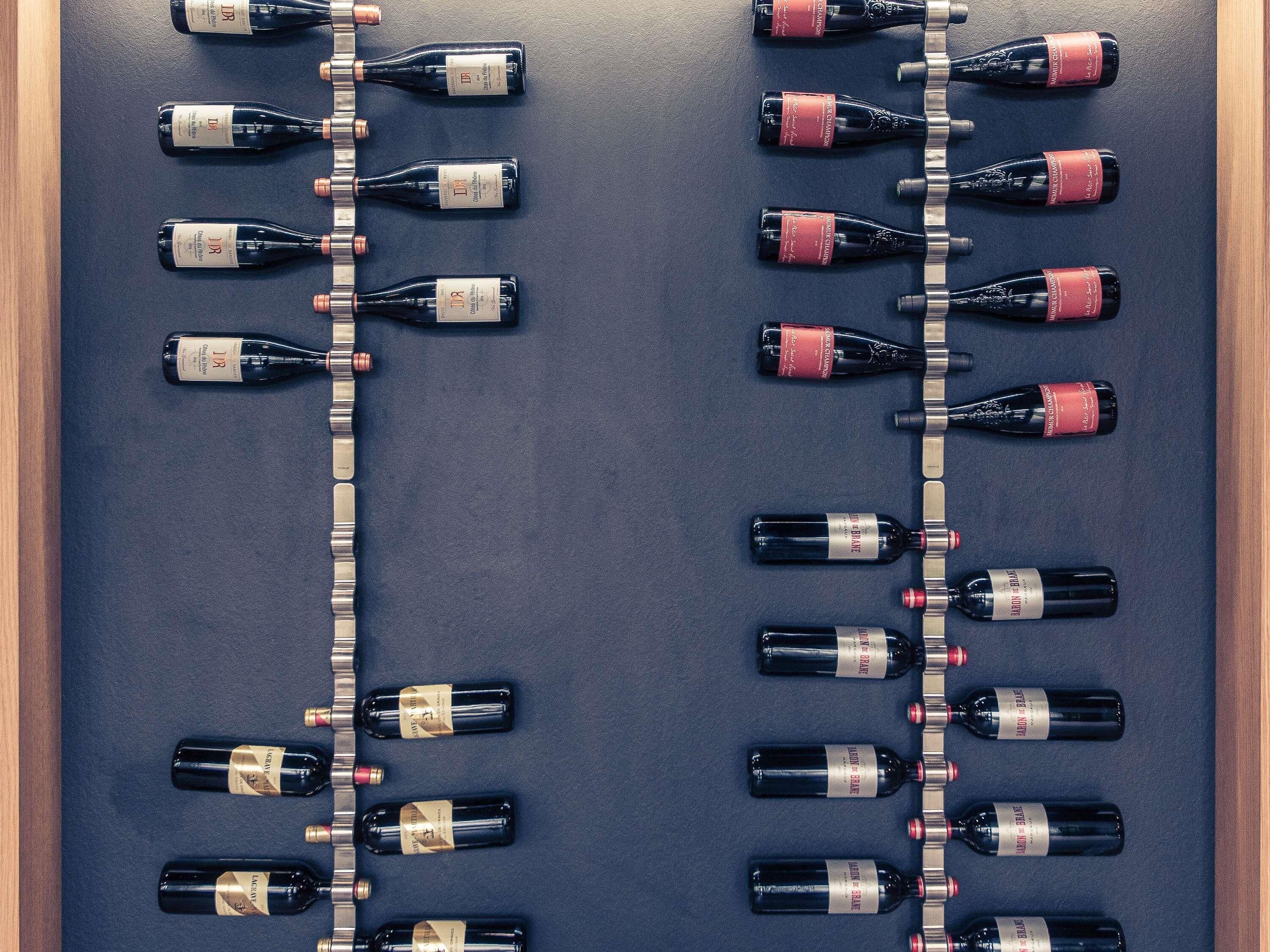 Two rows of wine bottles arranged on a dark surface, each row containing multiple bottles.