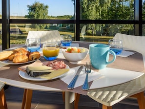 Taula de l'esmorzar amb croissants, formatge, fruita i una tassa blava.