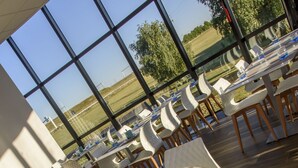 A dining area with tables and chairs, large windows, and a view of the outdoors. - Mercure Poitiers Site du Futuroscope Hotel (Chasseneuil-du-Poitou)