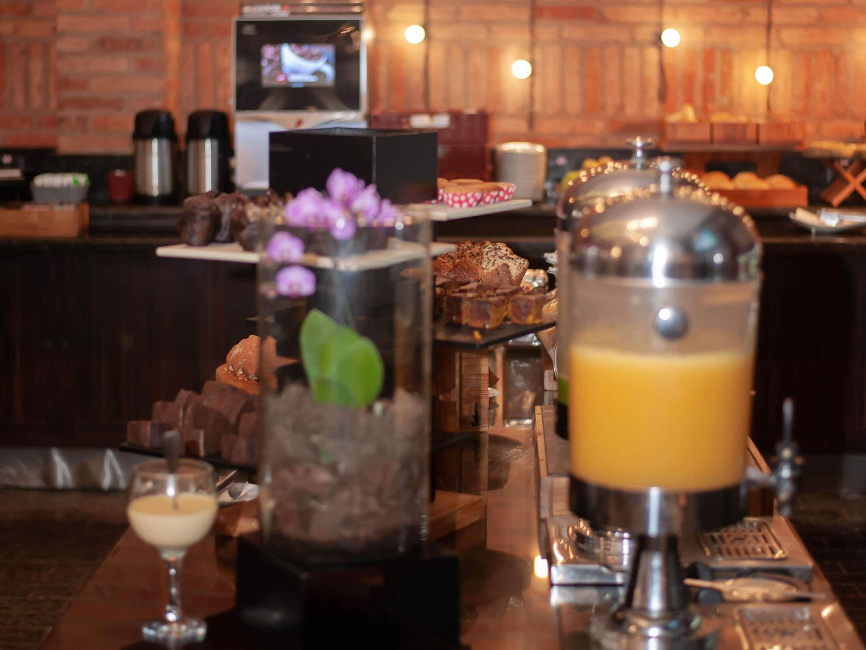 A bar area with a coffee machine, a drink dispenser, and a display of pastries.