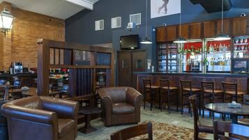 A bar area with leather seating, a bar counter with a red backdrop, and a visible menu board.
