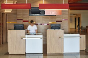 Un mostrador de recepción con un cartel que dice “ONLINE CHECK-IN” y una pantalla de televisión encima.