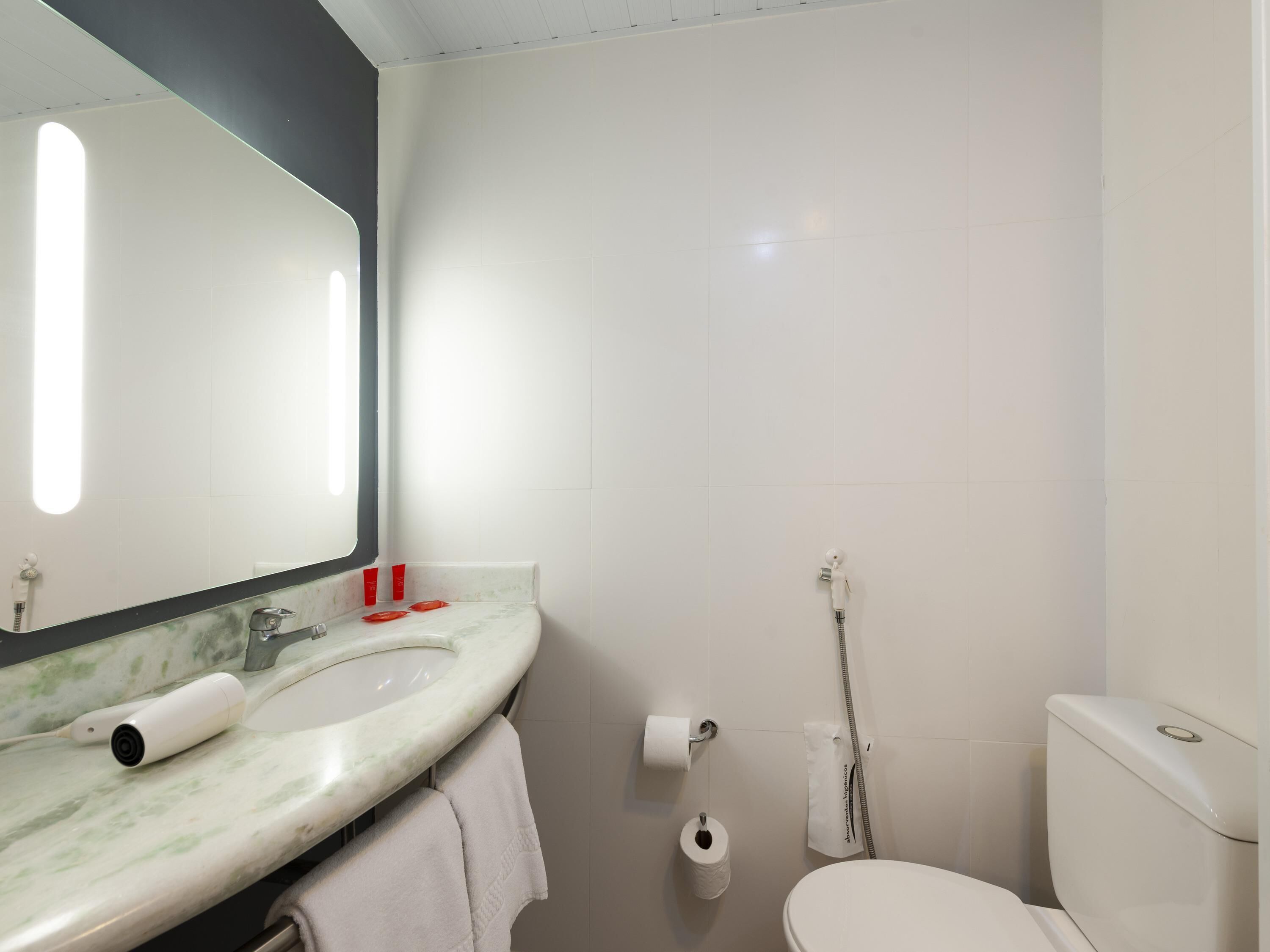 A bathroom with a white sink, mirror, toilet, and shower.