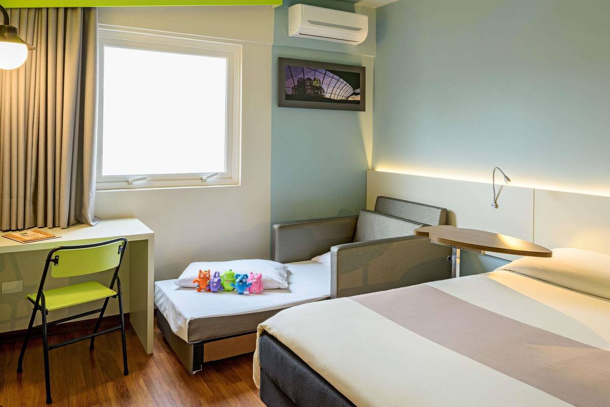 Een hotelkamer met een bureau, stoel, bed en nachtkastje.