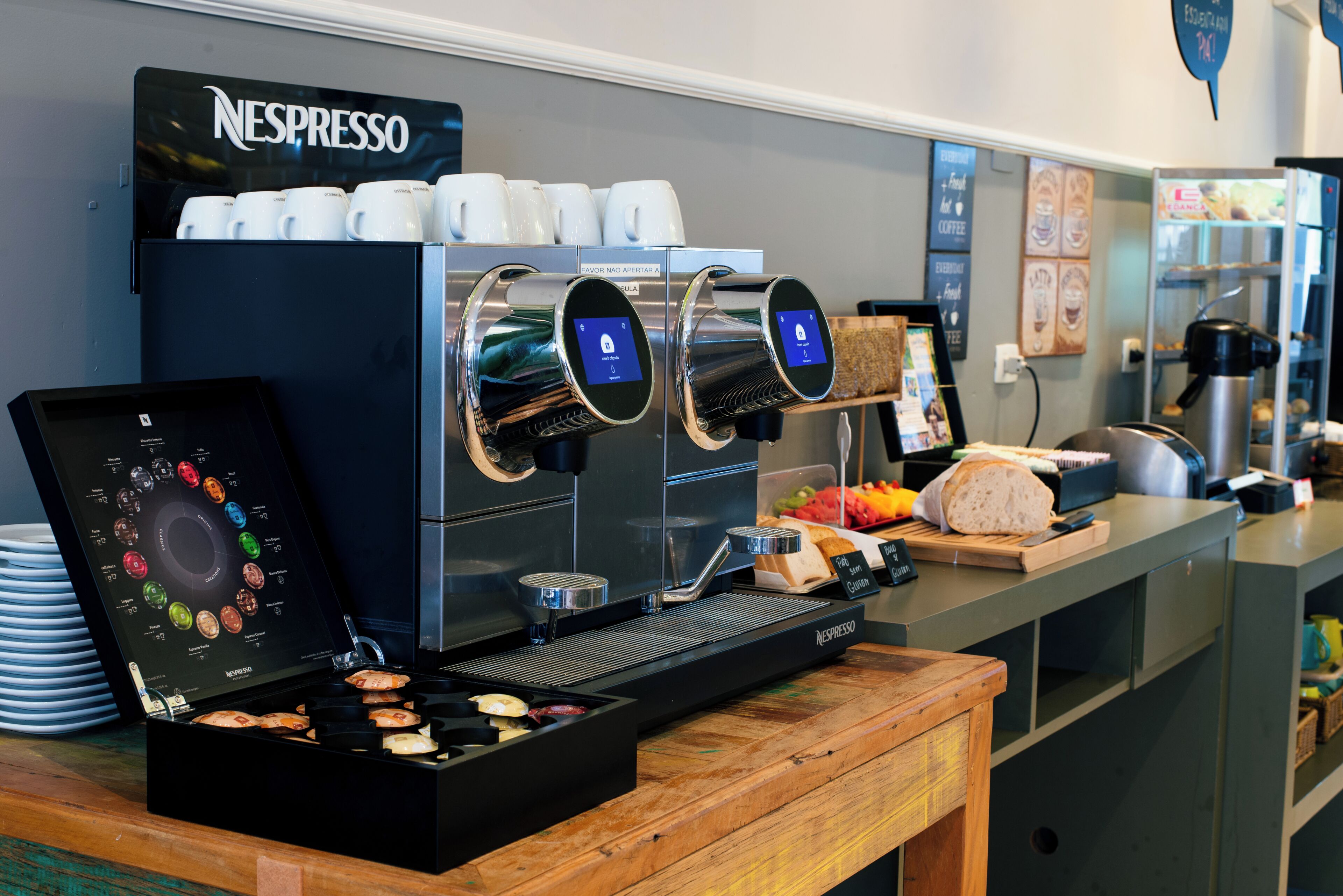Una estación de café con una máquina de espresso, una exhibición de tazas de café y una variedad de pasteles.