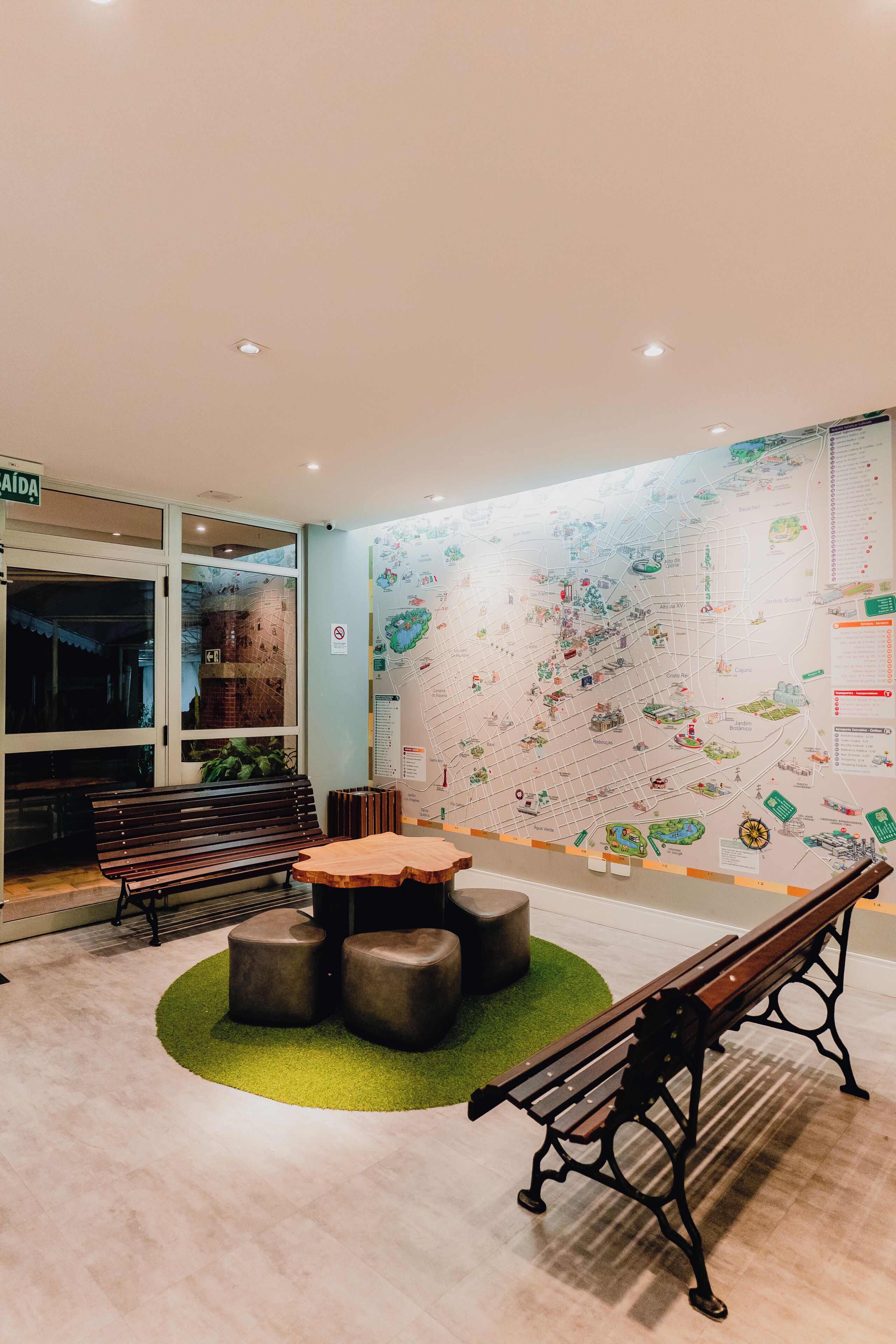 Un vestíbulo con un mapa, bancos y una mesa.