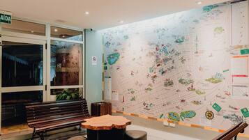 Un vestíbulo con un mapa, bancos y una mesa.