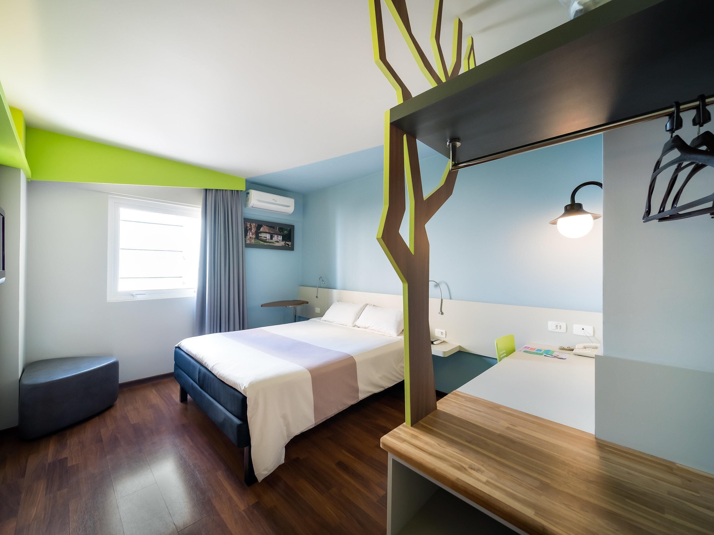 Una habitación de hotel con cama, mesita de noche y escritorio con silla.