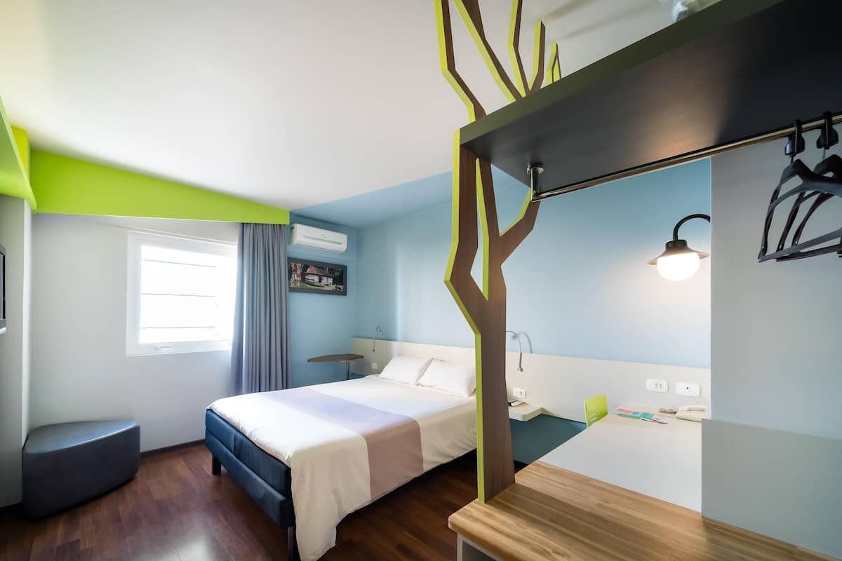 Een hotelkamer met een bed, nachtkastje en een bureau met stoel.
